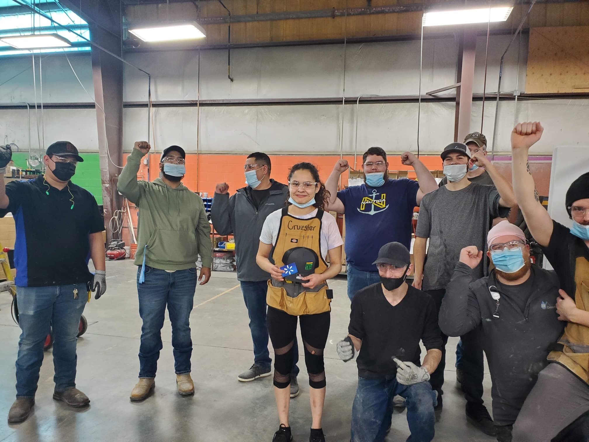 A diverse group of individuals wearing masks, raising their hands in a gesture of solidarity or celebration.
