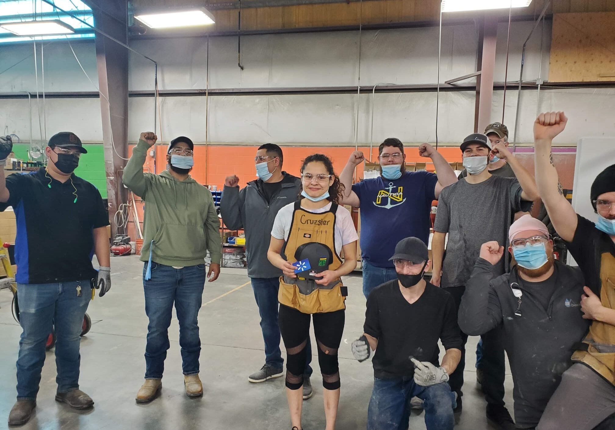 A diverse group of individuals wearing masks, raising their hands in a gesture of solidarity or celebration.