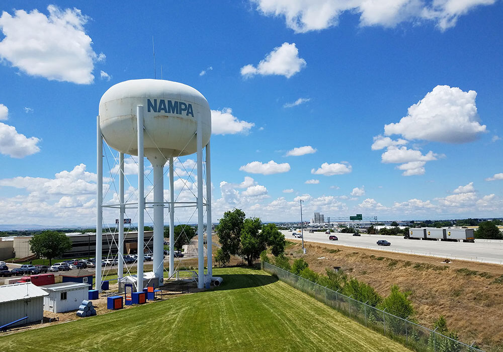 A large white water tower featuring a prominent blue sign on its side